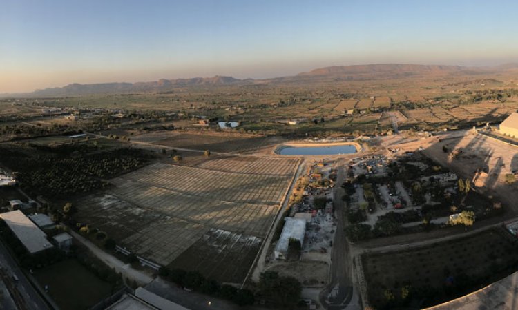 The view from the plant's preheater tower at dusk, with the clinker and cement silos on the left, the plant's orchards in the centre, raw meal silo and limestone shed at the right and the hills of the Salt Range in the distance.
