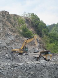 A 385 C series large hydraulic excavator loads an awaiting 769 D series off-highway truck at the Ryougami-Kougyou company quarry. Off camera  another truck waits to be loaded.