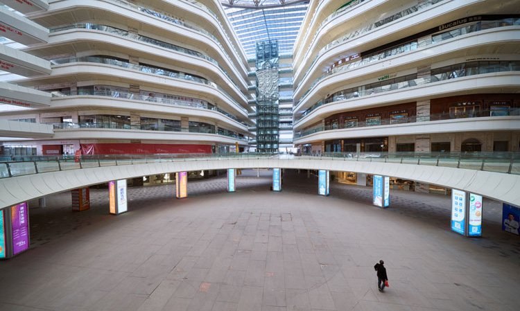 A lone shopper walks through an empty mall in Foshan, China, in 2018. Credit: Rick Wang / Shutterstock.com.